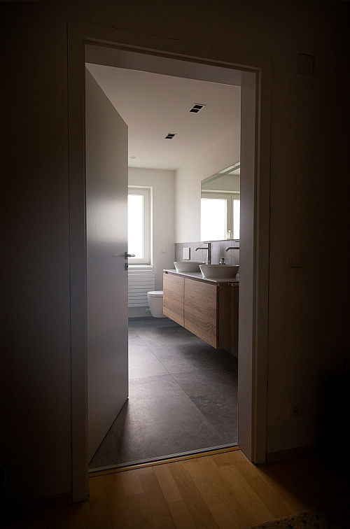 Blick durch offene Tür ins Badezimmer mit Echtholzwaschtisch und Doppel-Aufsatzbecken.