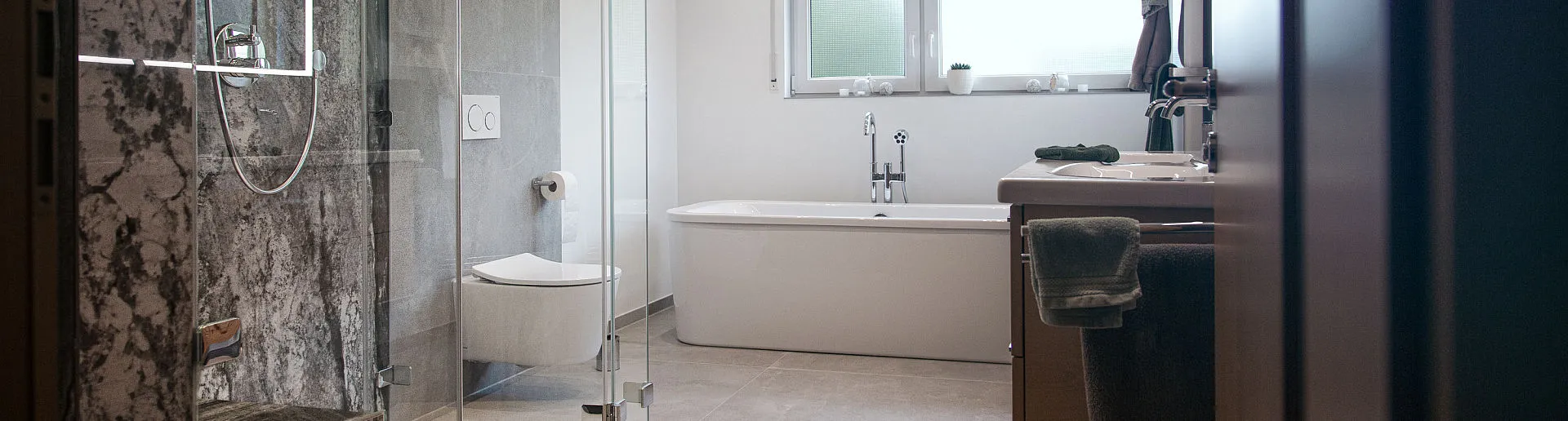 Modernes Badezimmer mit freistehender Badewanne, Glasdusche und stilvollem Waschtisch in warmen Erdtönen.
