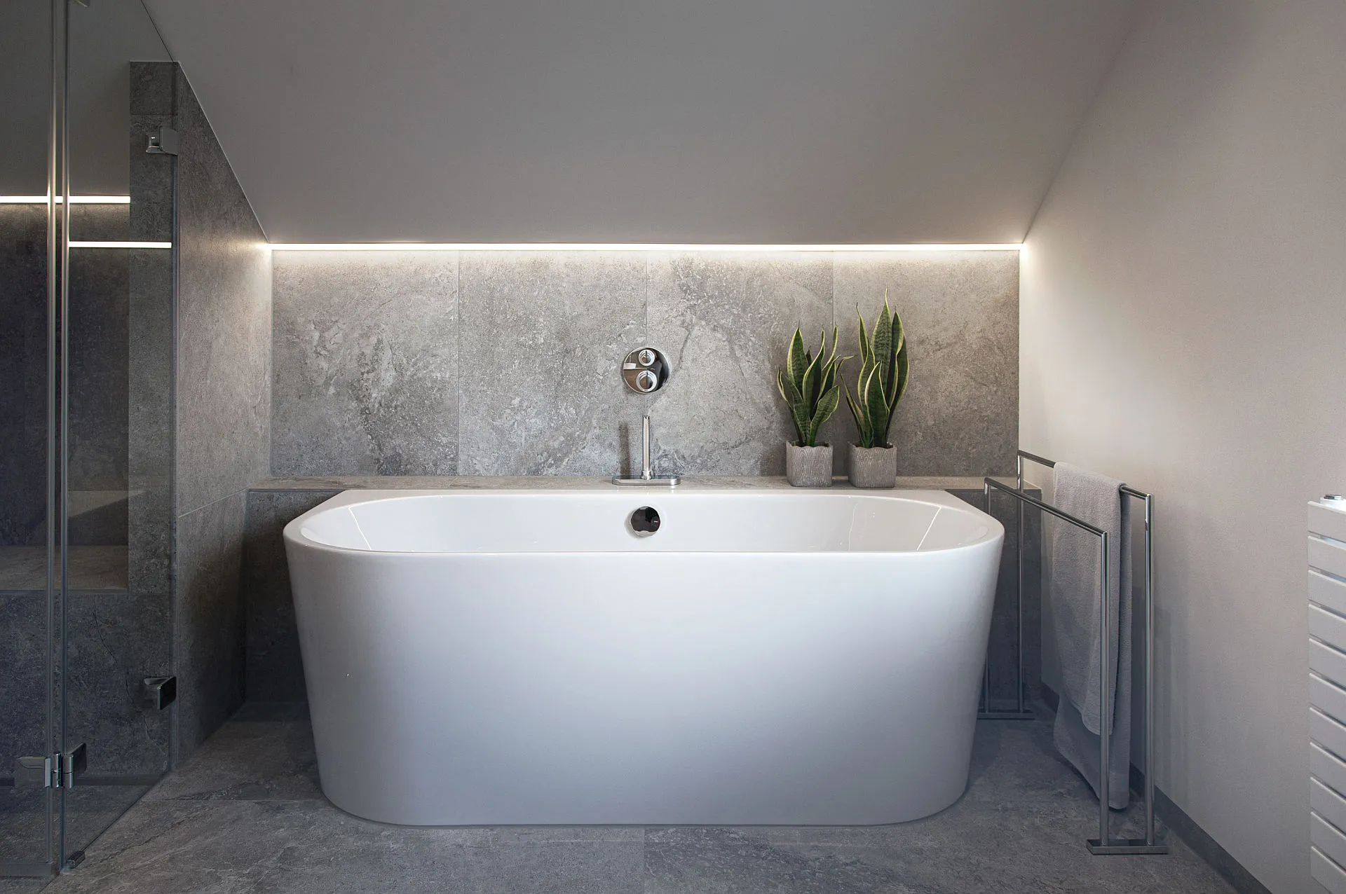 Freistehende, wandmontierte Badewanne unter einer schrägen Decke mit stimmungsvoller LED-Beleuchtung.