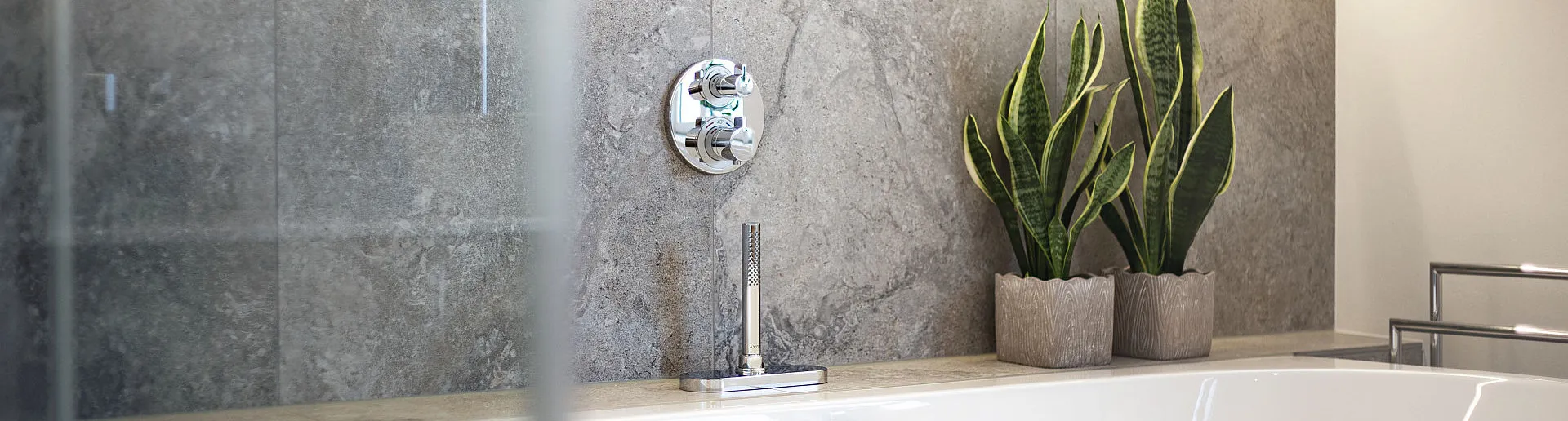 Eine wandstehende Badewanne ist vor einer mit Natursteinfliesen verkleideten Wand positioniert.
