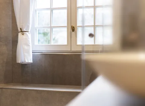 Fenster mit weißem Vorhang in einem Jugendstilbad. 