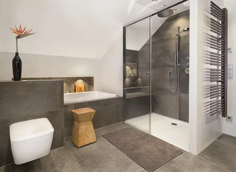 Luuxus-Badezimmer mit ebenerdiger Dusche, Naturfliesen, Holzelementen und einer in die Wand eingelassenen Badewanne.