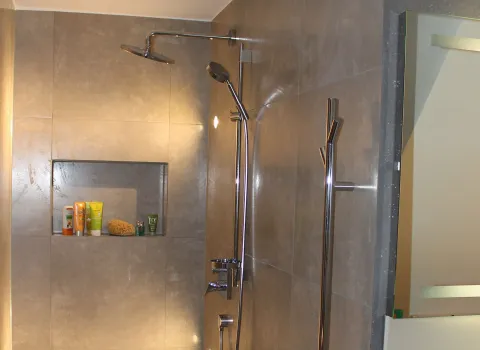 Grau beflieste Dusche mit einer luxuriösen Regenbrause und einer Handbrause in glänzendem Chrom.