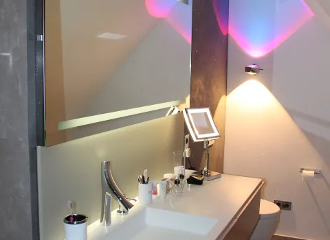 Rosa-gold beleuchteter Waschplatz mit breitem Waschbecken und eine elegante Mischbatterie aus Chrom.