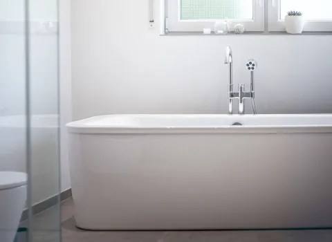 Freistehende Badewanne vor einem großen Fenster mit Milchglas.