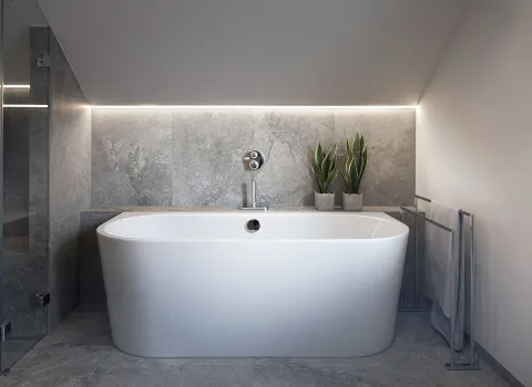 Freistehende, wandmontierte Badewanne unter einer schrägen Decke mit stimmungsvoller LED-Beleuchtung.