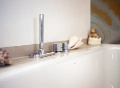 Ausschnitt einer Badewanne mit Duscharmatur und Muscheln als Dekoration