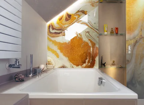 Badewanne mit Armatur und Rückwand des Bades aus Glas mit Farbenspiel aus Marmor und Gold
