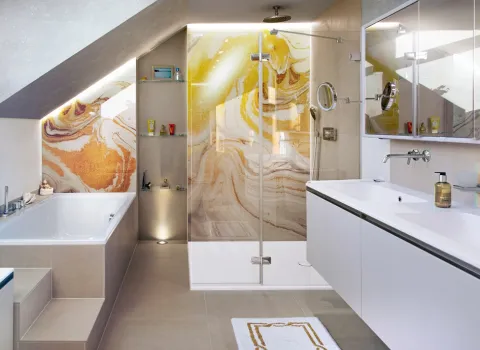 Badezimmer mit Badewanne, Dusche, Doppelwaschtisch, Spiegelschrank und Rückwand aus einem Farbenspiel aus Marmor und Gold