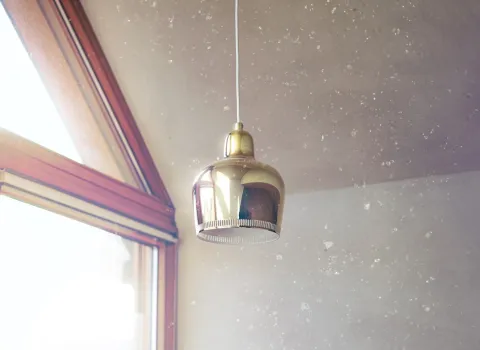 Vergoldete Deckenlampe vor Glimmerputz und Fenster