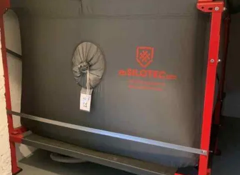 Ein großes, graues Textilsilo mit rotem Metallrahmen steht in einem Lagerraum.