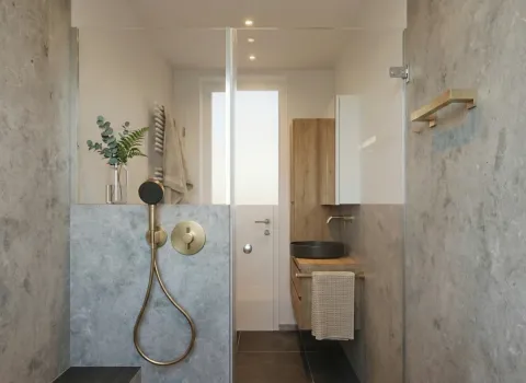 Stilvolles Duschbad mit Holzwaschtisch, schwarzem Aufsatzbecken und goldener Armatur.