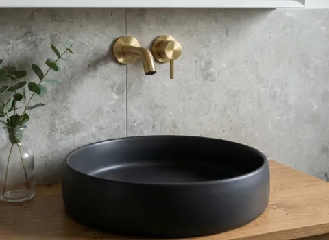 Duschbad mit Charakter, Holzwaschtisch mit schwarzem Aufsatzbecken, goldener Wandarmatur und grauer Steinrückwand.