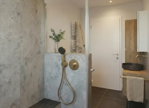 Hochwertiges Duschbad mit Steinwand, Handtuchhalter und harmonischer Materialästhetik.