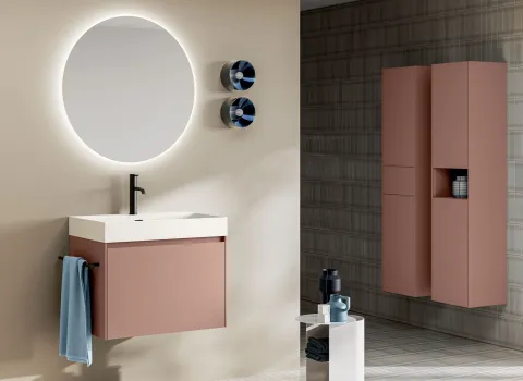 Moderner Waschtisch mit roséfarbener Front, weißem Aufsatzbecken und rundem LED-Spiegel kombiniert mit passendem Hochschrank in zeitloser Badgestaltung von Stocco.
