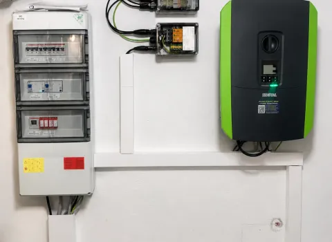 Eine professionelle Elektroinstallation für eine Photovoltaikanlage mit KOSTAL Wechselrichter ist an einer weißen Kellerwand montiert. Neben dem Wechselrichter sind Sicherungsverteiler, Schutzmodule und Anschlusskästen sauber installiert und miteinander verbunden. Die Anlage ermöglicht die effiziente Einspeisung und Nutzung von selbst erzeugtem Solarstrom.