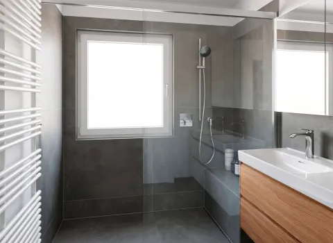 Dusche mit Fensterlicht und grauen Fliesen