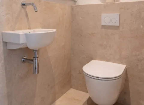 Kleines Waschbecken mit Chromarmatur im WC‑Bereich