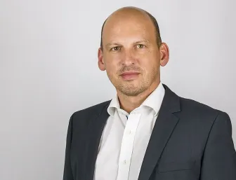 Geschäftsführer Andreas Staib vor grauem Hintergrund.