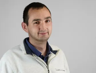 Kundendienstleiter Nicolai Greipel vor grauem Hintergrund.