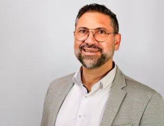 Mario Pisu vor grauem Hintergrund.