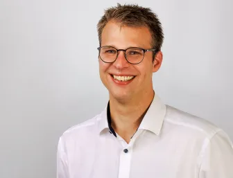 Sebastian Kühn vor grauem Hintergrund.