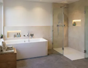 Badezimmer mit einer geräumigen Dusche und separater Badewanne. Beleuchtete Wandnischen neben beiden Bereichen setzen Pflegeprodukte stilvoll in Szene.