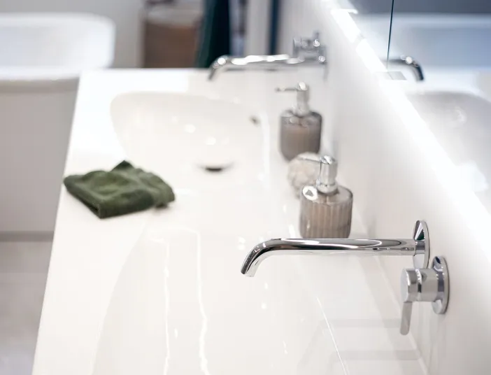 Detailaufnahme eines weißen Doppelwaschbeckens mit minimalistischen Wandarmaturen.