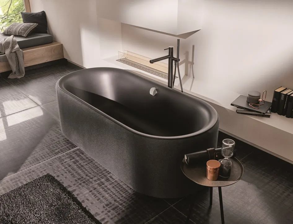 Badewanne BetteLux Oval Couture in Schwarz auf dunklen Fliesen vor heller Wand 